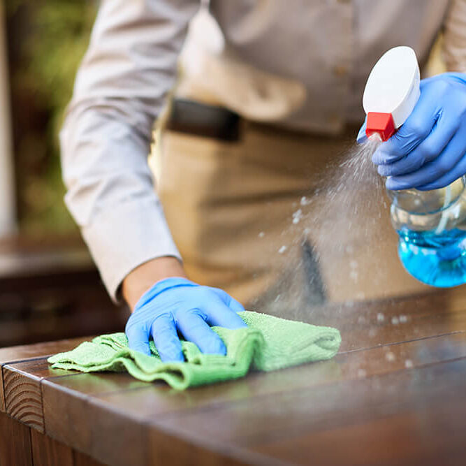 closeup-waitress-disinfecting-tables-outdoor-cafe